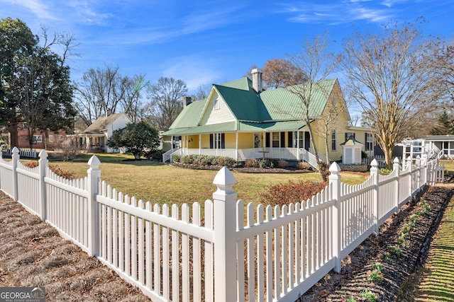 view of front facade featuring a fenced front yard, a front yard, covered porch, and metal roof