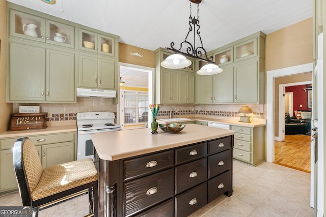 kitchen featuring electric stove, light countertops, under cabinet range hood, green cabinets, and backsplash