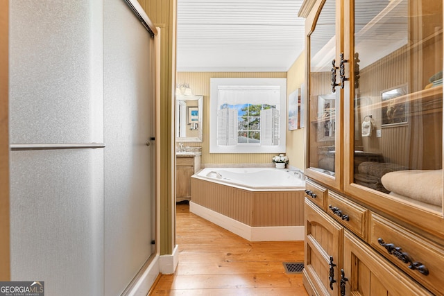 full bath with vanity, a shower stall, a bath, and hardwood / wood-style flooring