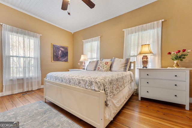 bedroom featuring ceiling fan, light wood finished floors, multiple windows, and visible vents