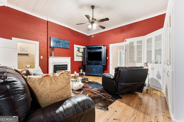 living room featuring light wood-type flooring, a fireplace, and a ceiling fan