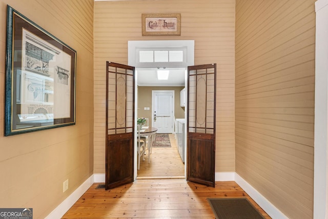 hall featuring light wood-style floors, visible vents, and baseboards