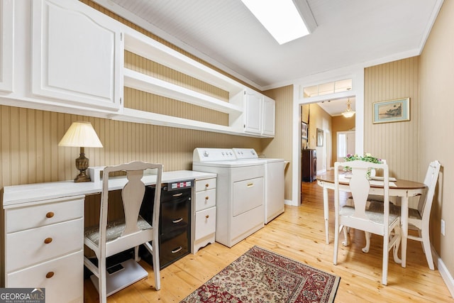 washroom featuring light wood-type flooring, cabinet space, baseboards, and washing machine and clothes dryer