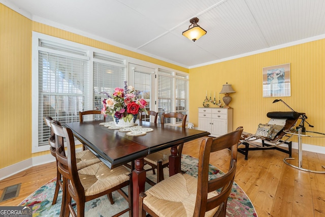 dining area with light wood finished floors, baseboards, visible vents, and ornamental molding