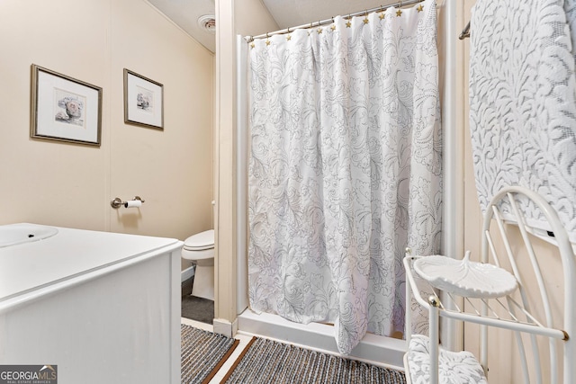 bathroom featuring toilet and curtained shower