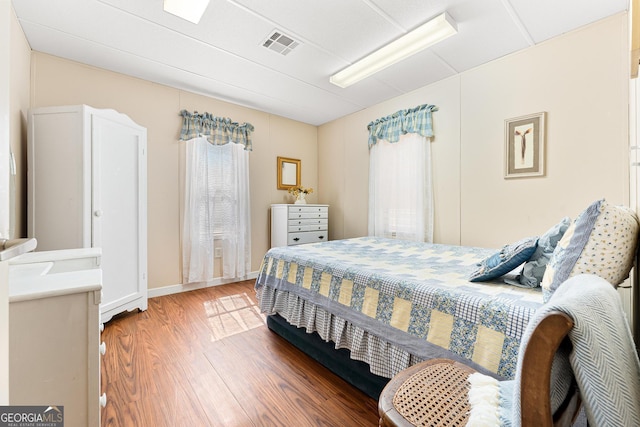 bedroom with wood finished floors, visible vents, and baseboards