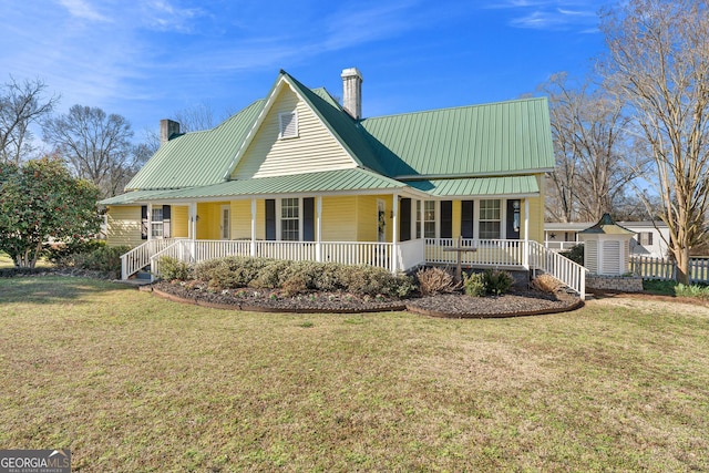 view of front of house with covered porch, a chimney, metal roof, and a front yard