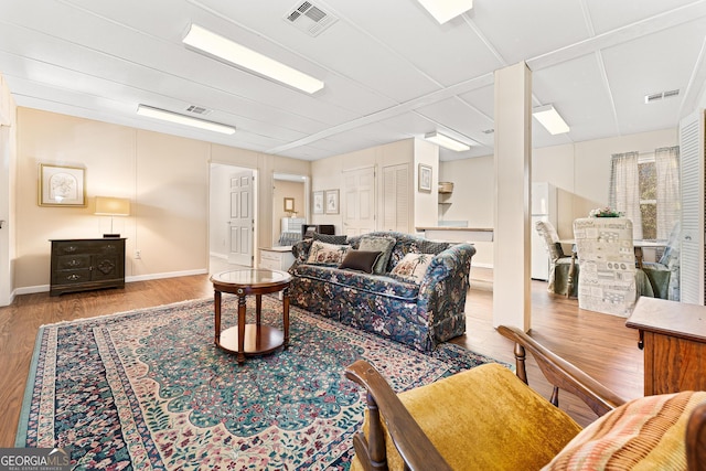 living area featuring baseboards, visible vents, and wood finished floors