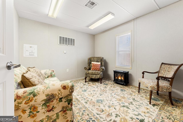 sitting room featuring carpet floors, a wood stove, and visible vents