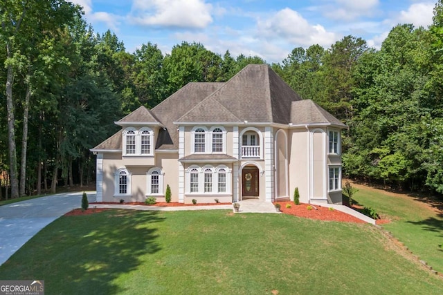 view of front of house with concrete driveway, roof with shingles, a front yard, and stucco siding