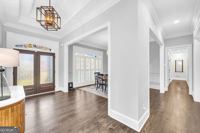 entryway with a notable chandelier, french doors, crown molding, and dark wood-style flooring