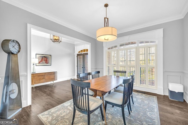 dining room with wood finished floors, a wainscoted wall, french doors, crown molding, and a decorative wall