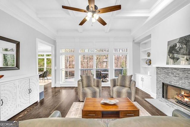 living area with beamed ceiling, built in features, coffered ceiling, wood finished floors, and a fireplace