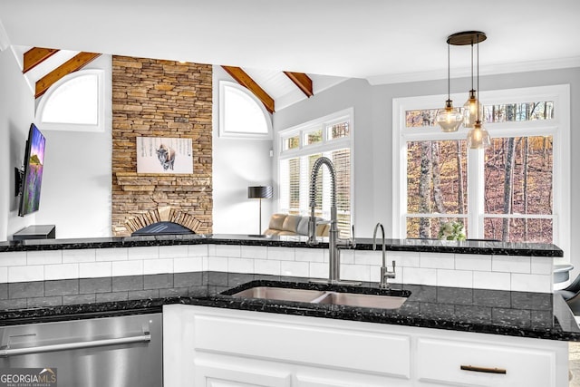 kitchen with dark stone countertops, dishwasher, white cabinetry, and a sink