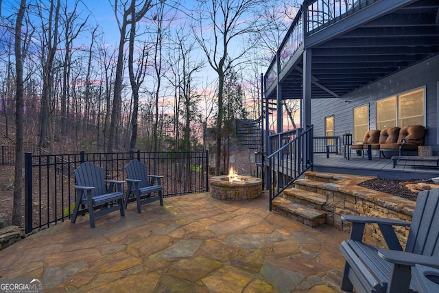 patio terrace at dusk with a deck and a fire pit