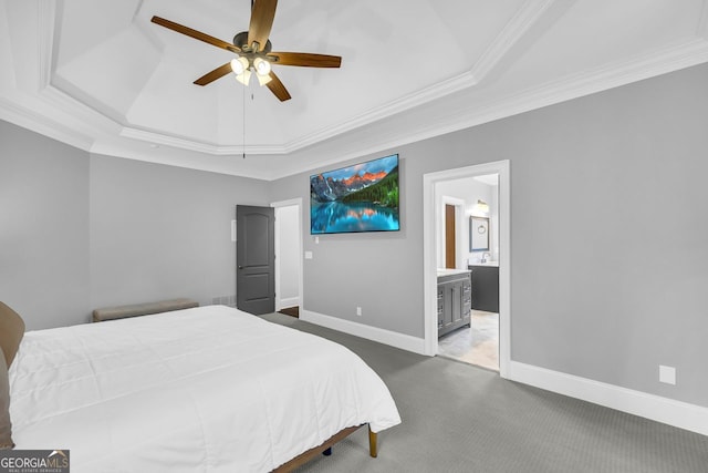 carpeted bedroom featuring a ceiling fan, a tray ceiling, ensuite bath, crown molding, and baseboards