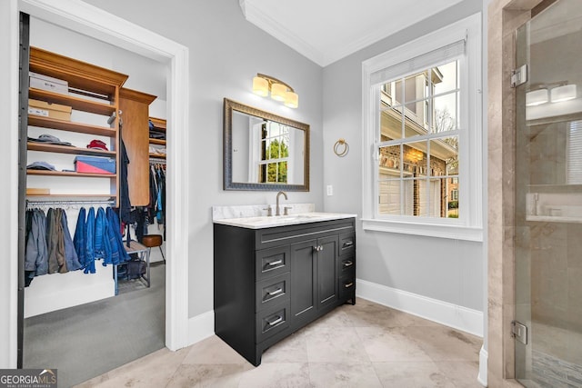 full bath featuring crown molding, vanity, a walk in closet, and baseboards