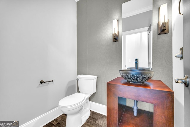 half bath with vanity, toilet, wood finished floors, and baseboards