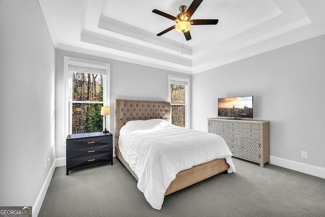 carpeted bedroom featuring multiple windows, baseboards, a tray ceiling, and ornamental molding