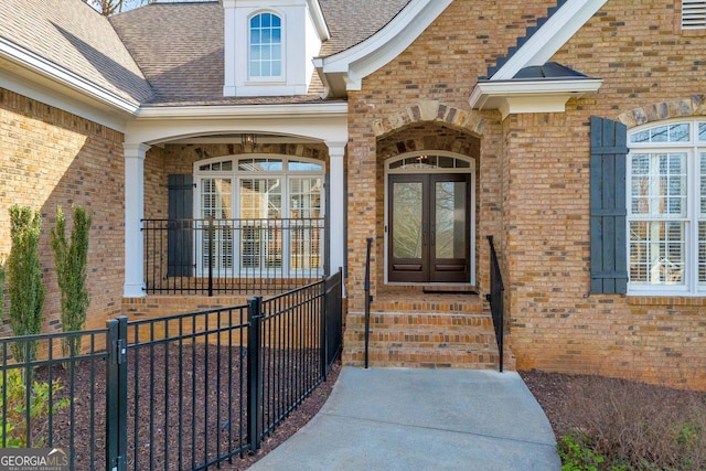 property entrance with french doors, brick siding, and a shingled roof