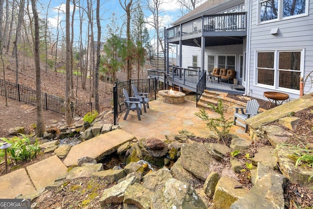 view of patio with a fire pit, a deck, a balcony, and fence