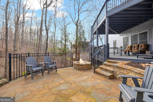 view of patio / terrace featuring a wooden deck, fence, and an outdoor fire pit