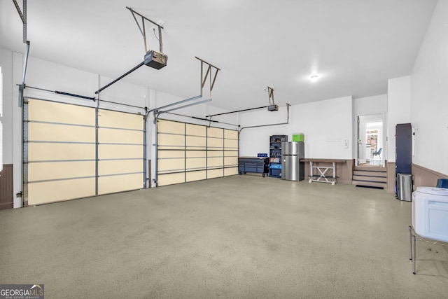 garage featuring freestanding refrigerator and a garage door opener