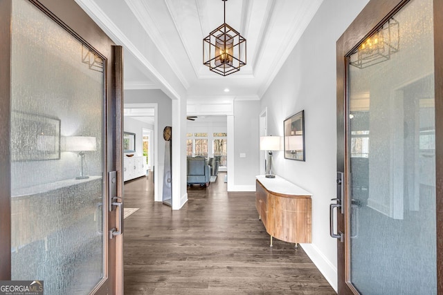 entryway featuring a chandelier, baseboards, ornamental molding, and dark wood-style flooring