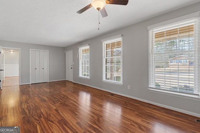 unfurnished bedroom featuring ceiling fan, wood finished floors, visible vents, and baseboards