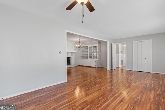 unfurnished living room featuring a fireplace, wood finished floors, and baseboards