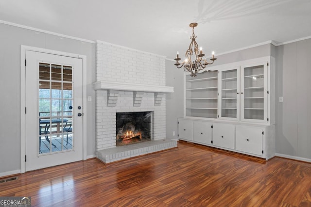 unfurnished living room featuring ornamental molding, a brick fireplace, visible vents, and wood finished floors