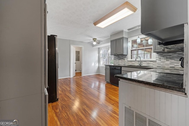 kitchen with tasteful backsplash, dishwasher, freestanding refrigerator, gray cabinets, and a sink