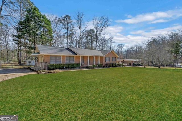 ranch-style house featuring driveway, brick siding, and a front yard