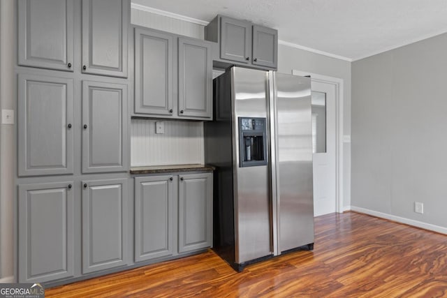 kitchen featuring dark wood-style flooring, baseboards, ornamental molding, gray cabinets, and stainless steel fridge