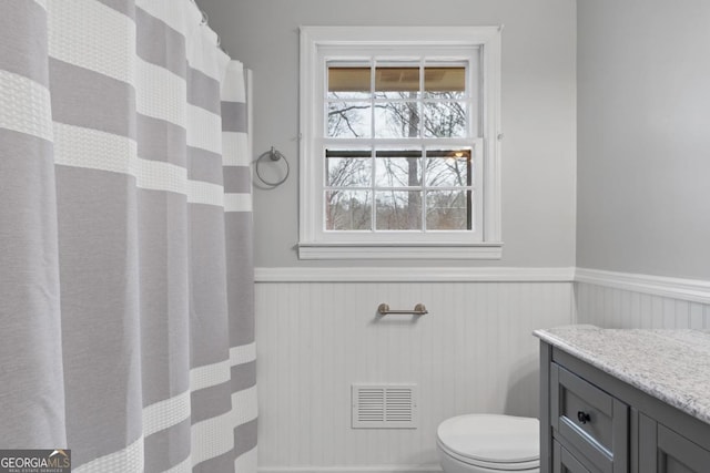 full bath featuring visible vents, toilet, a wainscoted wall, curtained shower, and vanity