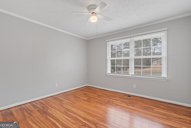 spare room with ornamental molding, wood finished floors, visible vents, and a healthy amount of sunlight