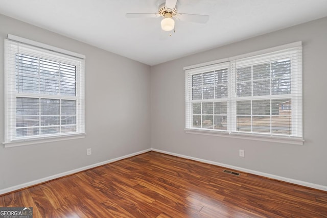 spare room with plenty of natural light, wood finished floors, and baseboards