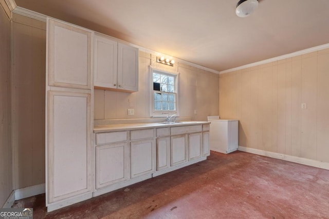 kitchen with baseboards, ornamental molding, light countertops, concrete flooring, and a sink