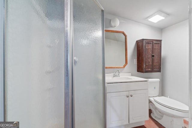 bathroom featuring a shower stall, toilet, and vanity