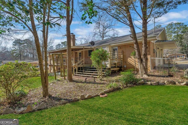 view of front of property with brick siding, a wooden deck, fence, and a front yard