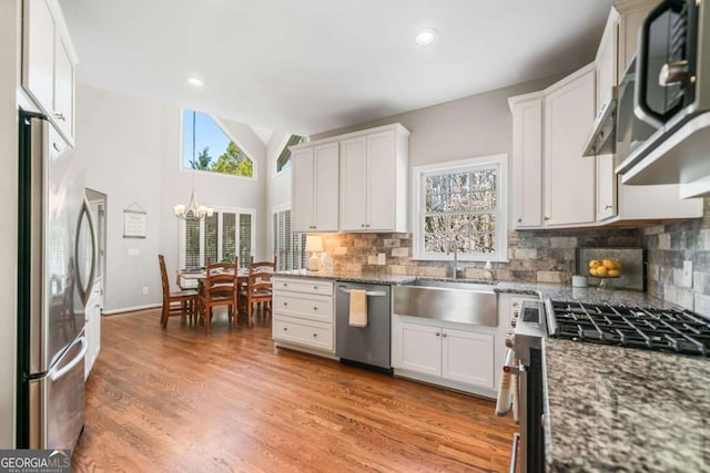 kitchen with appliances with stainless steel finishes, a sink, white cabinetry, and light wood-style floors