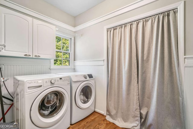 laundry area featuring light wood-style floors, washing machine and dryer, wainscoting, and cabinet space