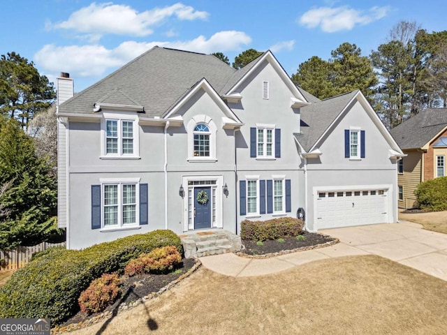 view of front of house with driveway, an attached garage, a chimney, and stucco siding