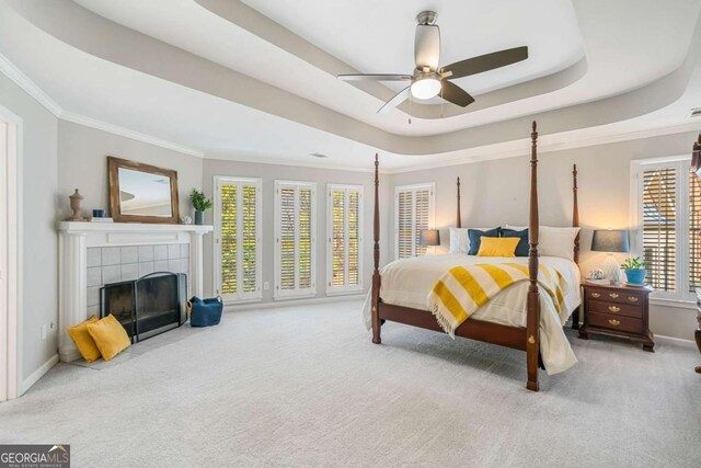 bedroom with ornamental molding, a raised ceiling, carpet flooring, and a fireplace