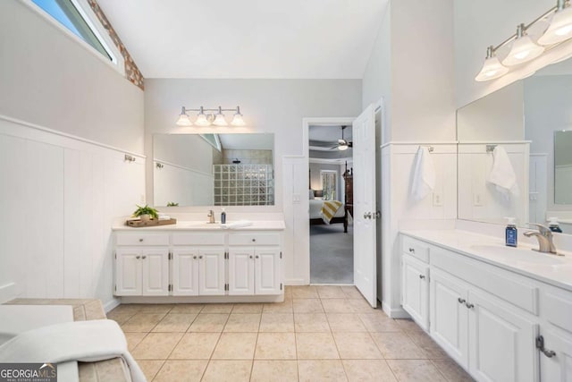 ensuite bathroom with tile patterned flooring, two vanities, a tile shower, and a sink