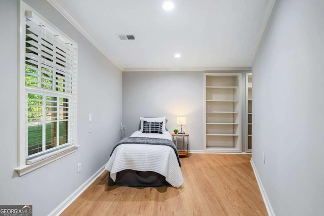 bedroom featuring ornamental molding, wood finished floors, visible vents, and baseboards