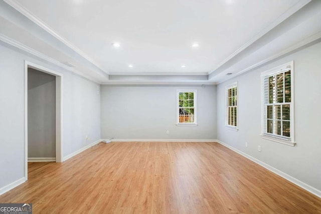 spare room featuring baseboards, a raised ceiling, and crown molding