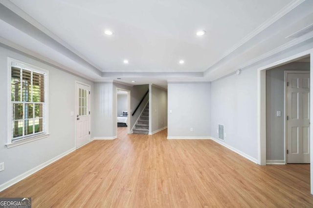 interior space with stairs, light wood finished floors, a raised ceiling, and baseboards