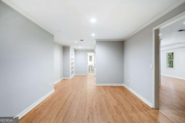 spare room with light wood-type flooring, crown molding, and baseboards