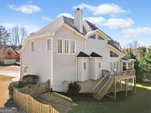 rear view of property featuring a chimney, stairway, roof with shingles, fence, and a wooden deck